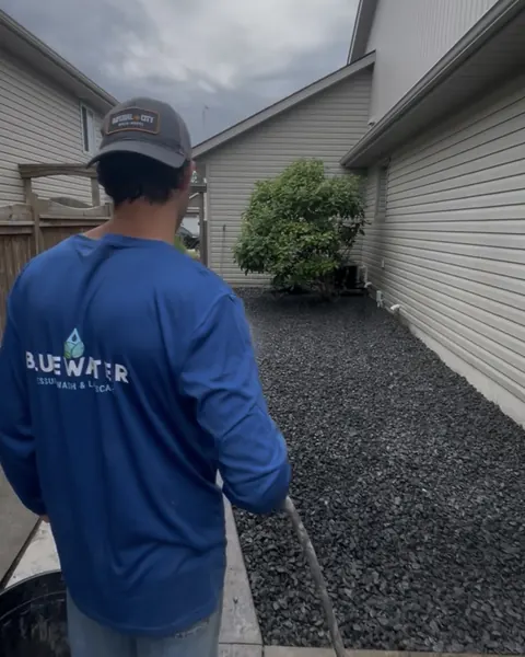Riley Barker, co-owner of Bluewater, rinsing a newly laid stone bed in a side yard