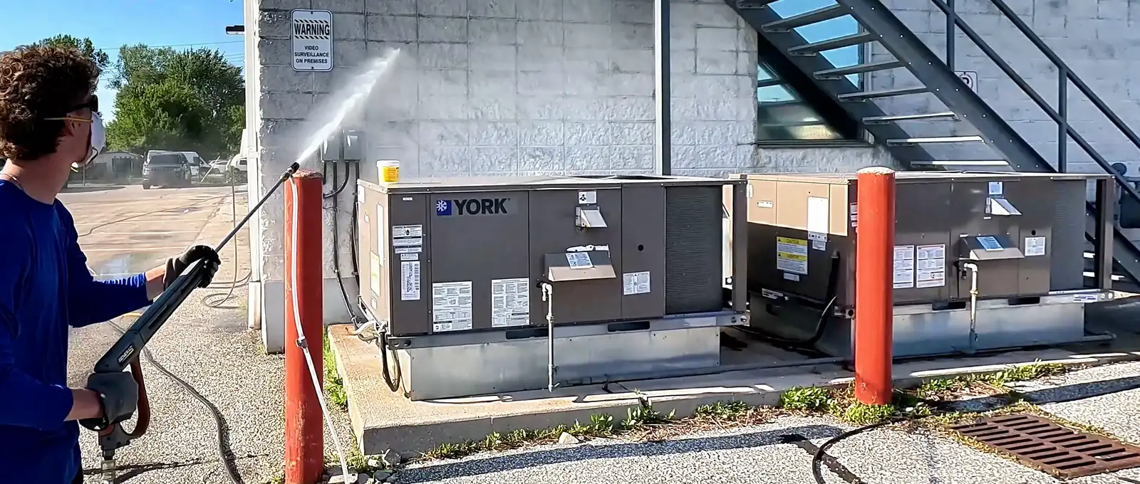 Bluewater crew member pressure washing the block wall of a commercial building
