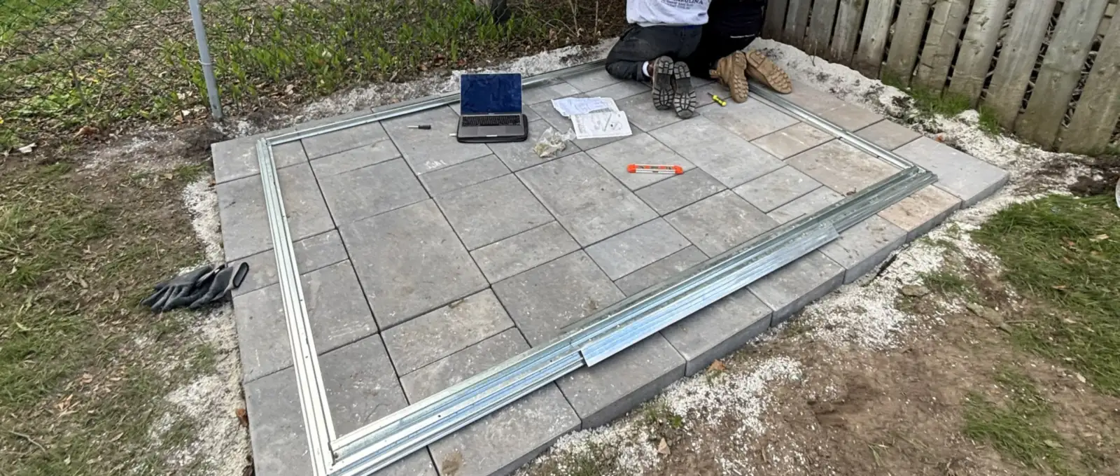 Bluewater crew member setting a new paver pad inside its edge restraint in a Sarnia-area back yard