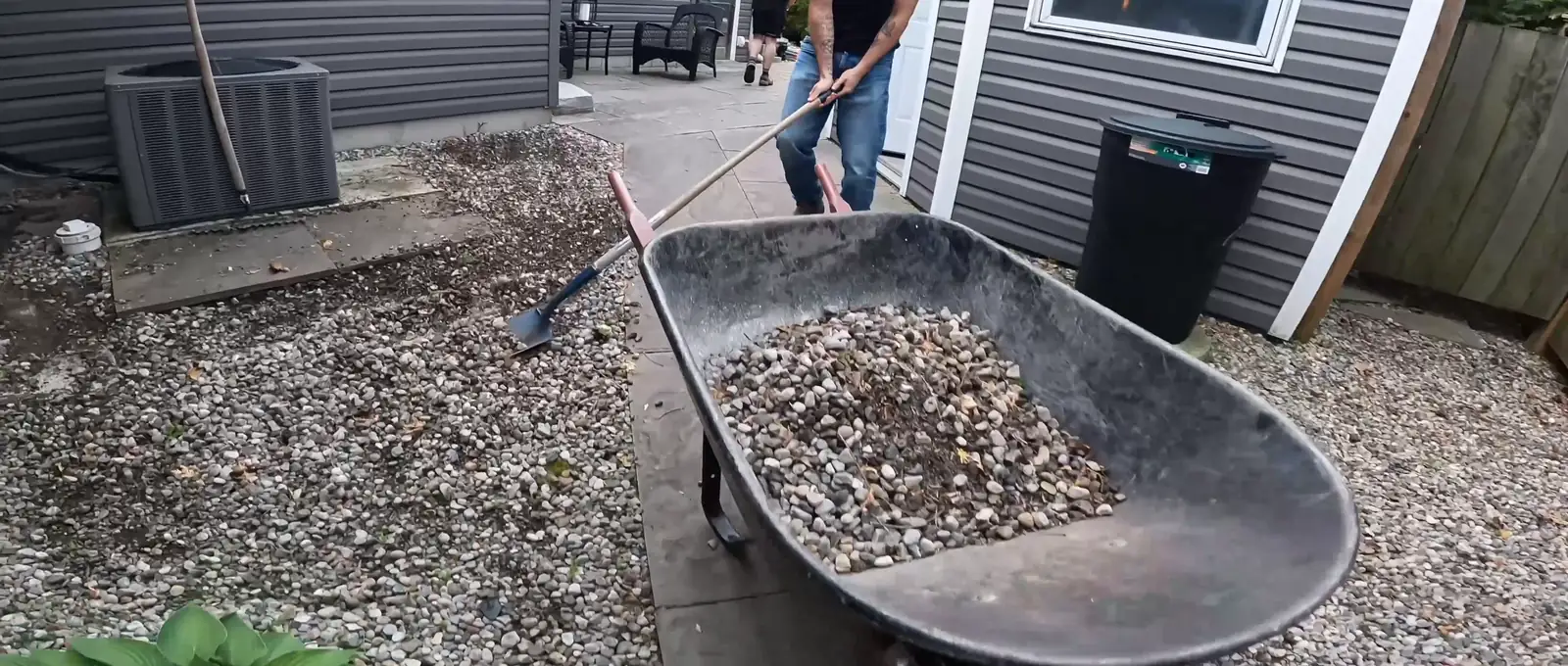 Bluewater crew member shovelling pea gravel from a wheelbarrow in a Sarnia-area side yard