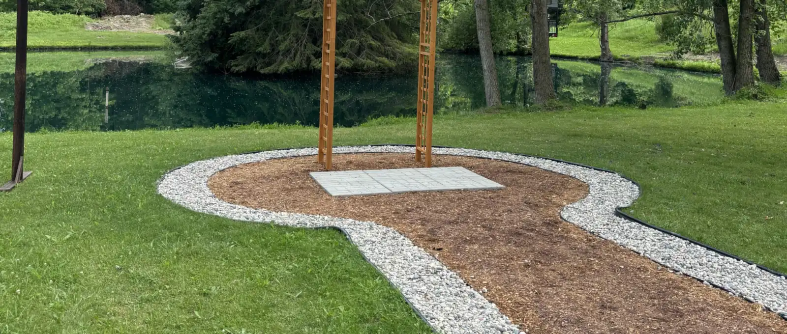 Finished landscape with a cedar arch, white stone circle and pathway beside a pond near Sarnia, Ontario