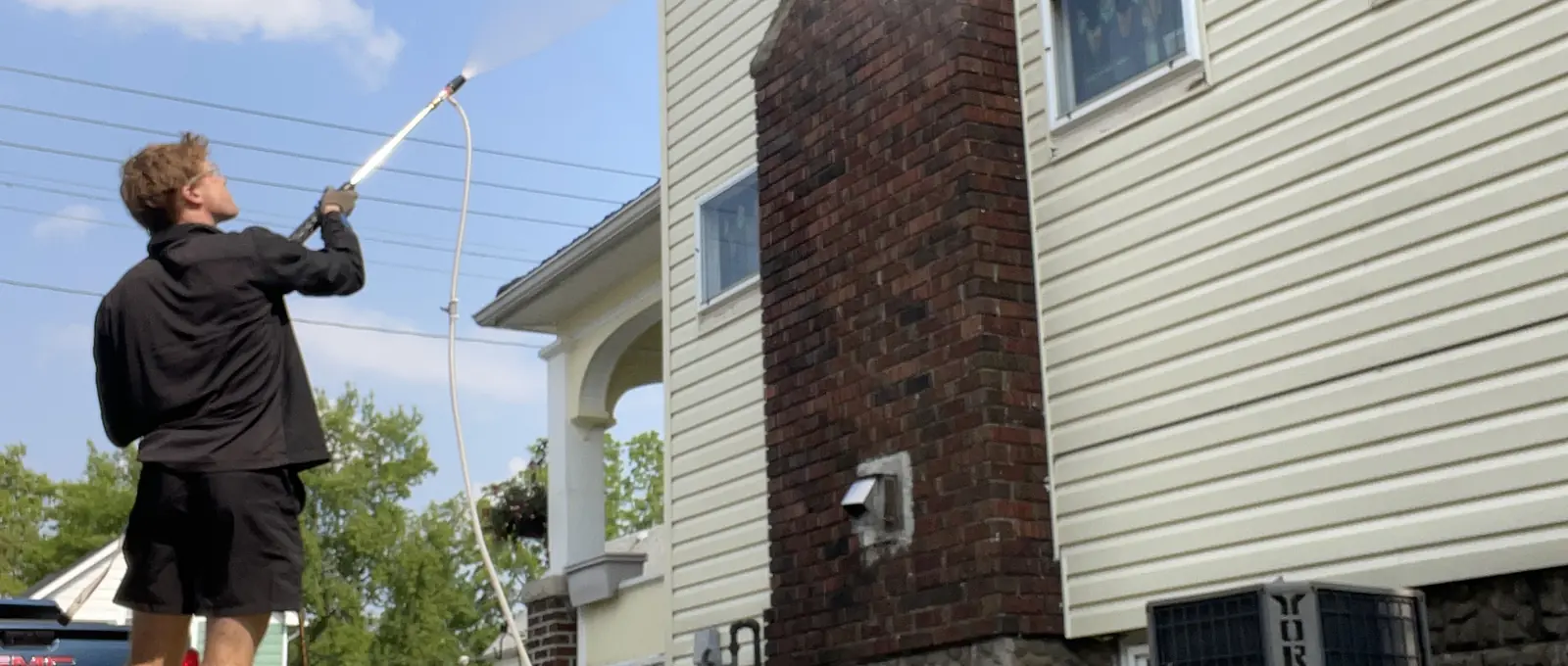 Bluewater crew member washing the upper siding of a two-storey home in Sarnia, Ontario