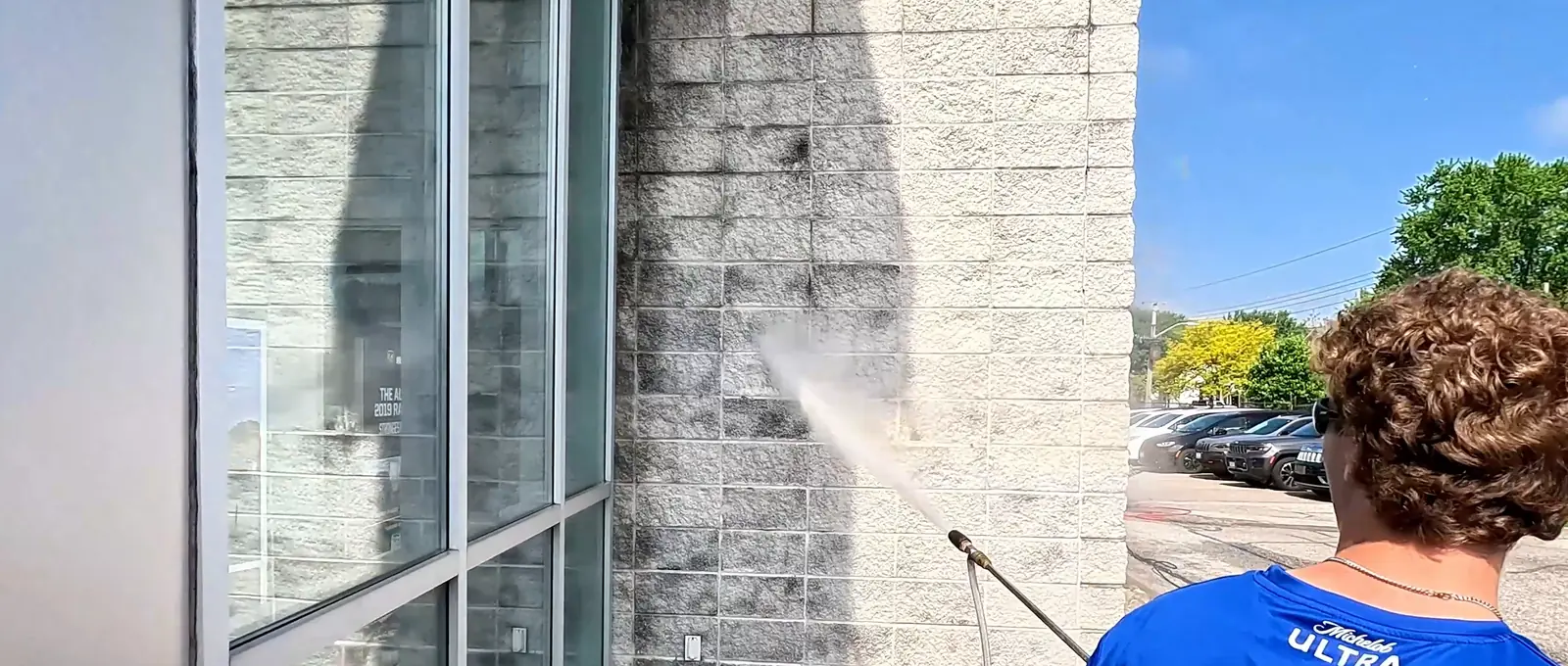 Bluewater crew member rinsing a glass wall on a commercial building in Sarnia, Ontario