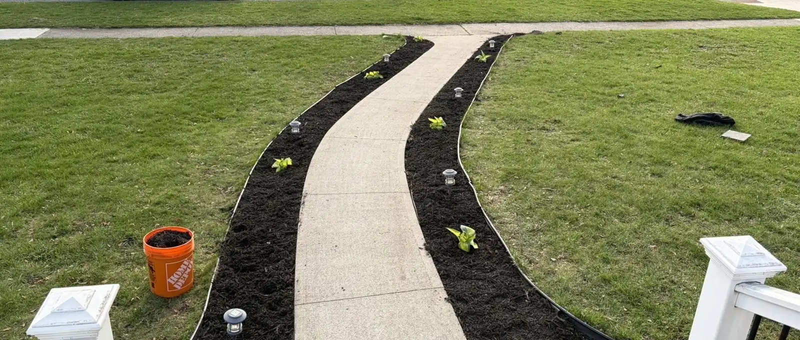 Concrete front walkway with freshly edged garden beds and new plants on a lawn in Sarnia, Ontario