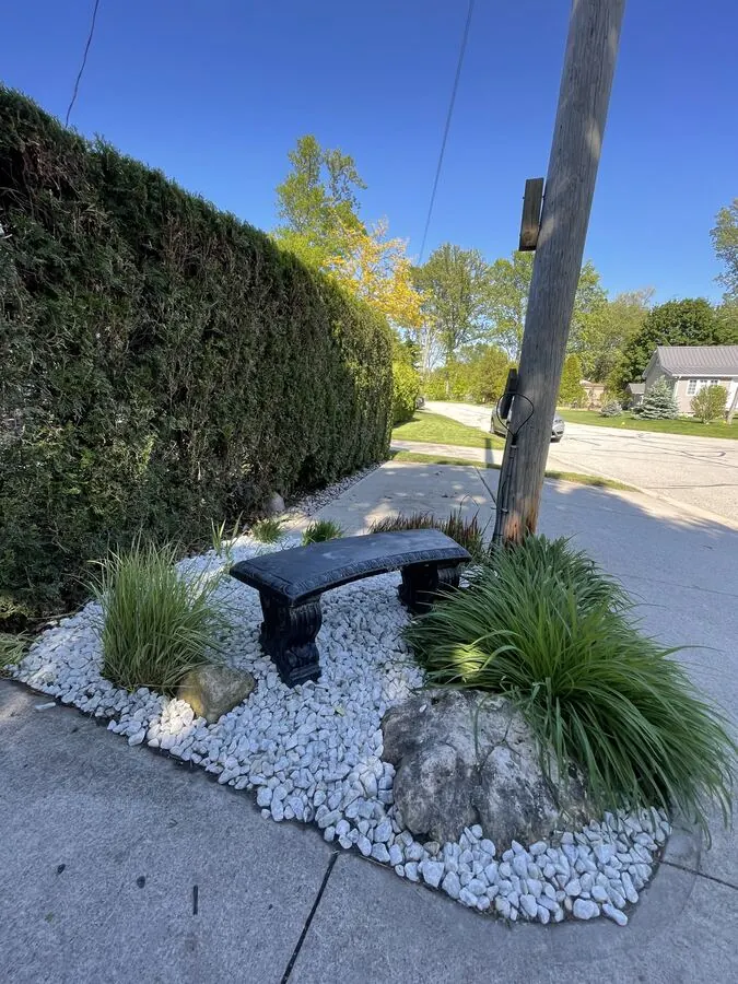 Corner rock bed with white stone, ornamental grasses and a bench
