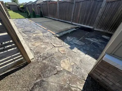 Flagstone patio laid in a side yard along a wood fence