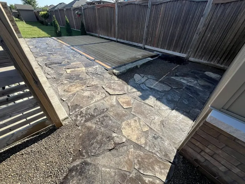 Flagstone patio laid along a side yard beside a wood fence