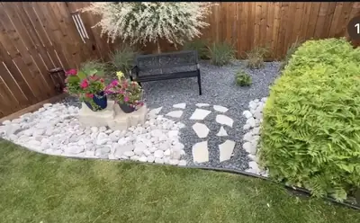 White stone bed with flagstone steps, a bench, shrubs and grasses