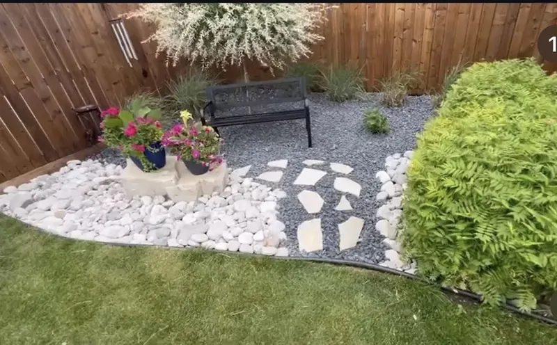 White stone garden bed with flagstone stepping stones and a bench